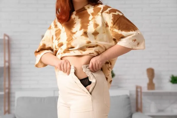 Image of woman trying to do her trousers up after pregnancy weight gain Thatcham